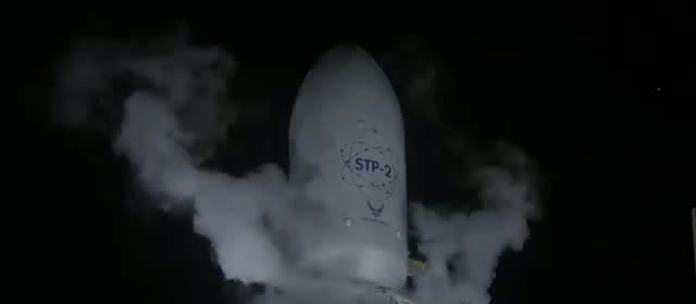 A Falcon Heavy fairing marked STP-2 in vapor during a night countdown
