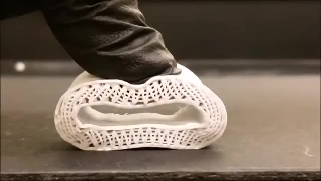A gloved hand pressing a white 3D-printed bone lattice