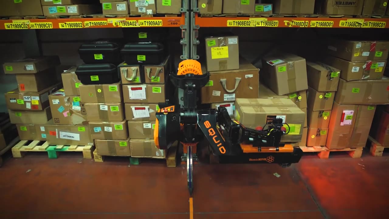 Orange Squid robot climbing warehouse rack rails with a cardboard box
