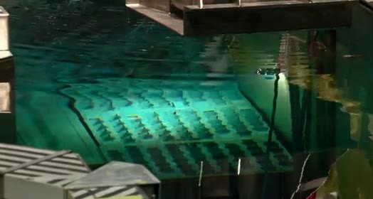 Spent-fuel pool glowing blue-green above a grid of fuel assemblies