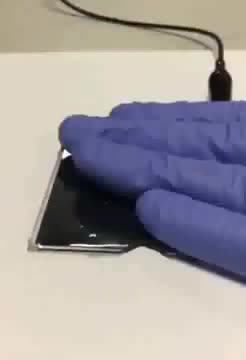 Gloved hands pressing a thin generator pad wired to a cable