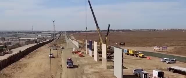 Crane setting tall concrete wall panels along a desert road