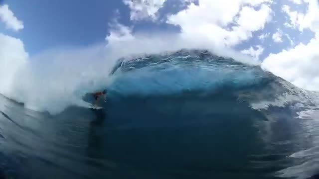 A hollow ocean wave, with the lip throwing over a turquoise barrel.