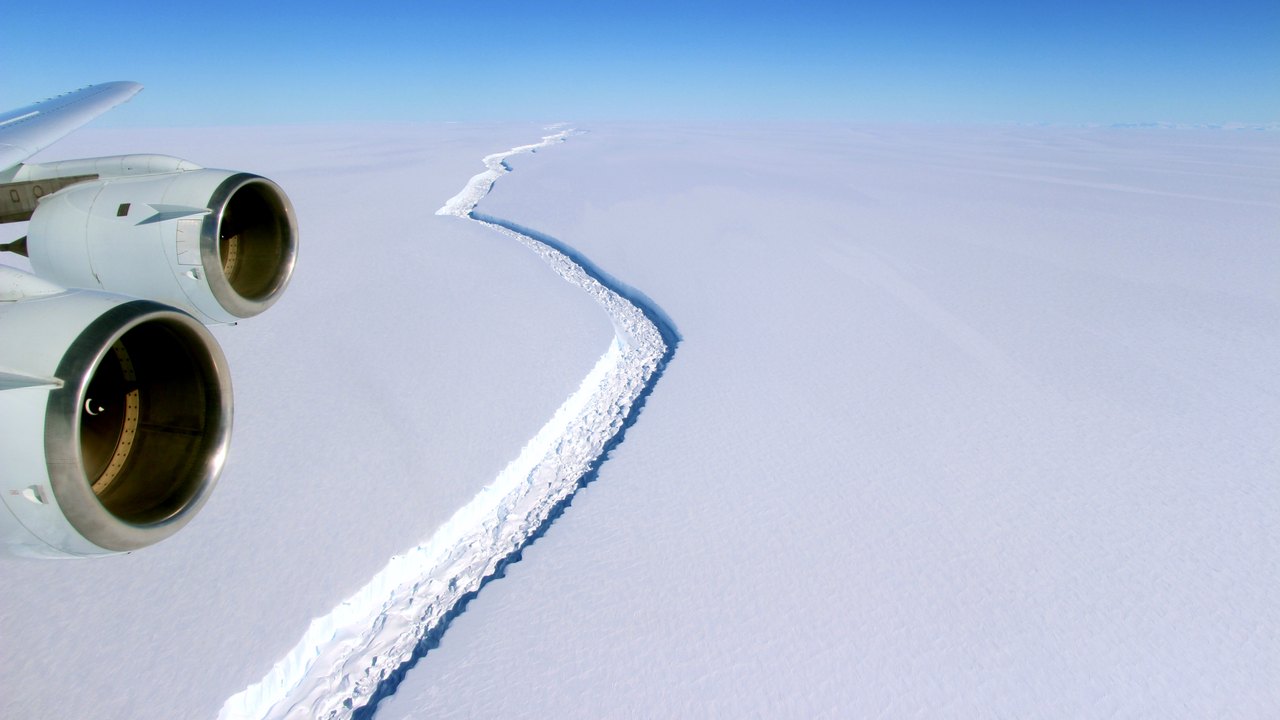 Aerial view from an aircraft of a long crack running across the white surface of the Larsen C Ice Shelf in Antarctica.