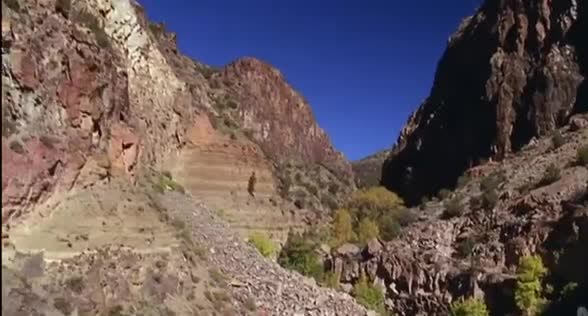Layered rock walls of a dry canyon under a clear sky.