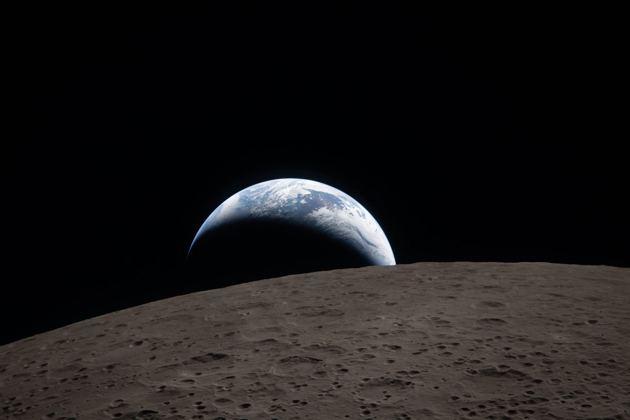 Crescent Earth setting behind the cratered lunar horizon, photographed by the Artemis II crew on April 6, 2026