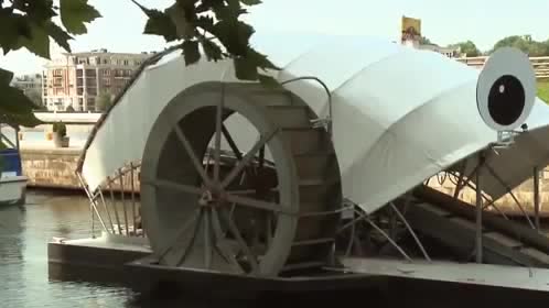 A waterwheel on a barge in a river.