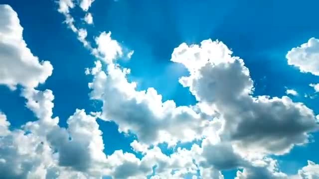 Sunlight scattering through a field of white clouds in a blue sky.