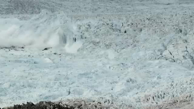 A glacier face collapsing into a cloud of ice and spray