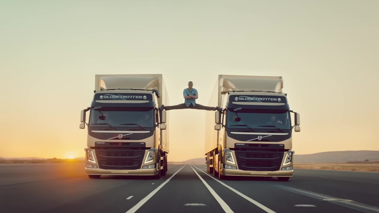 Jean-Claude Van Damme in a full split between two reversing gold Volvo trucks at sunset