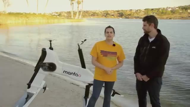 Two people with white hydrofoil boards beside a lake