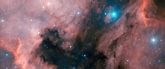 A star-forming nebula with pink gas, dark dust lanes, and bright blue-white stars.