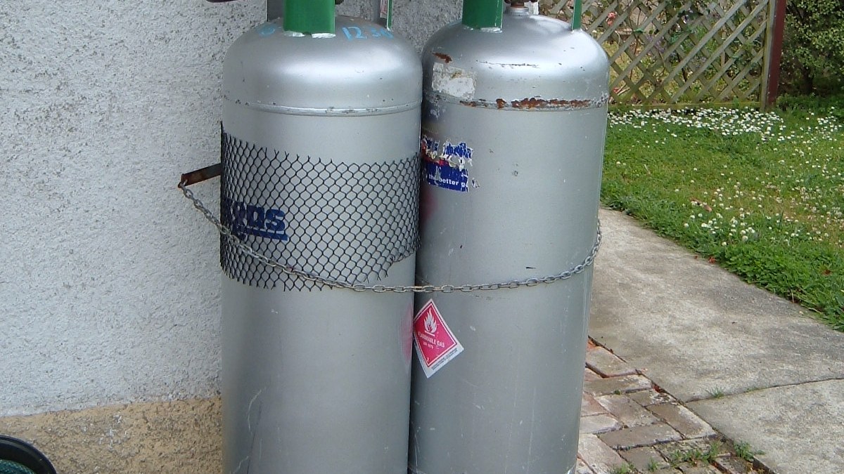 Two LPG gas cylinders standing against a wall