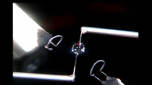 A small flame held between metal rods in darkness