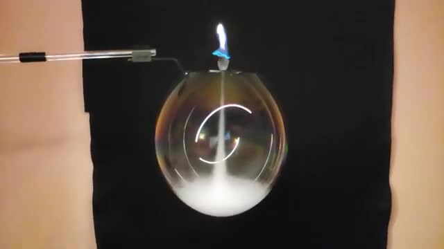 A flame sitting on a smoke-filled soap bubble.