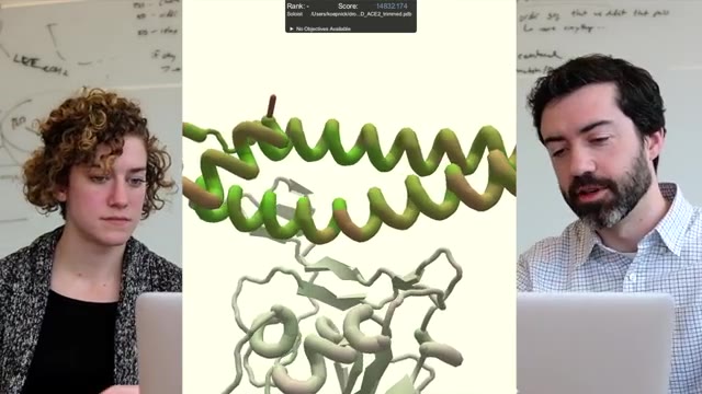 Protein model on a screen beside two people at a laptop