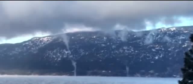 Thin funnels of mist over a lake.