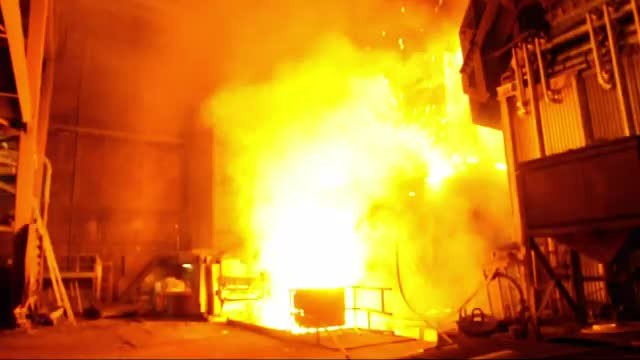 Molten metal glowing yellow-white as it pours inside a furnace.