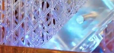 A tall clear lattice coming out of a vat of liquid resin on a rapid 3D printer.