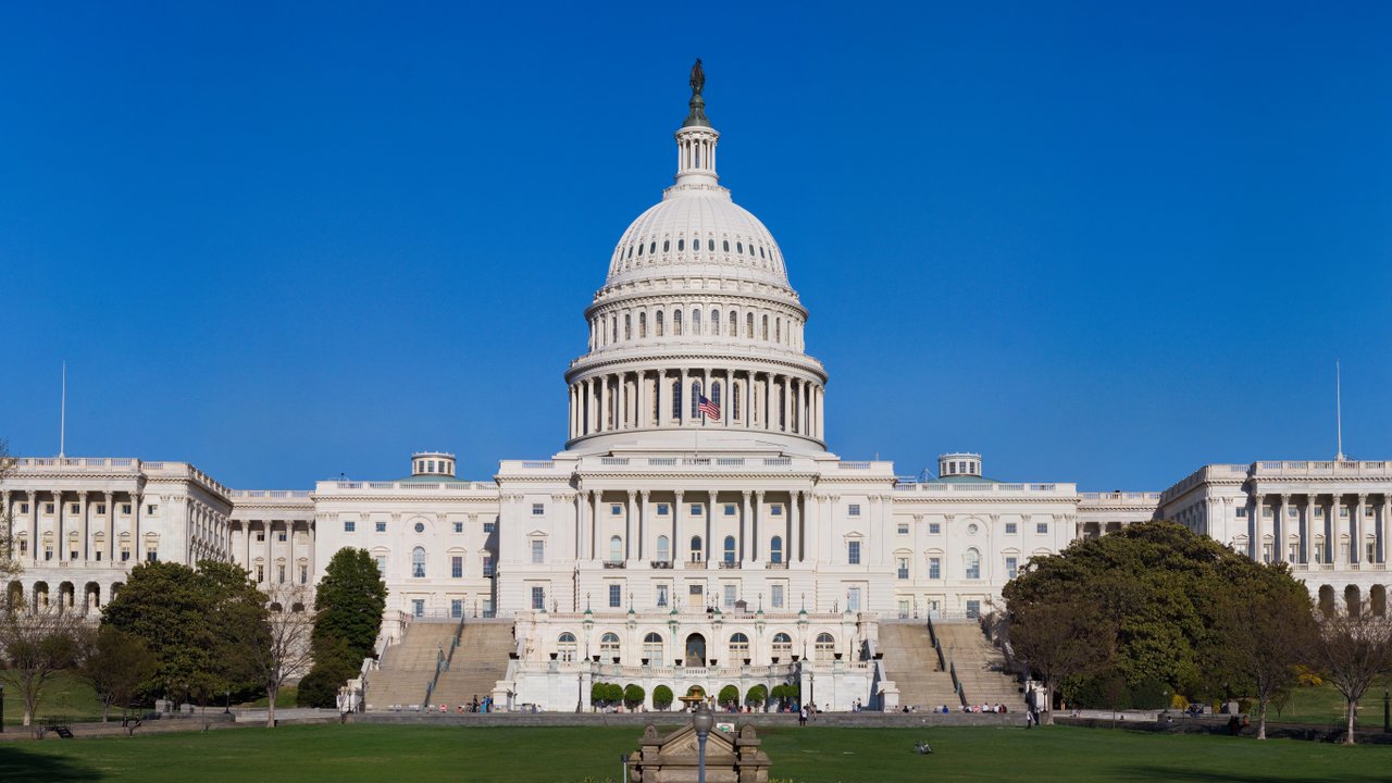 The west front of the United States Capitol and its white dome under a clear blue sky.