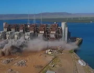 Dust rising as a power-station stack comes down.