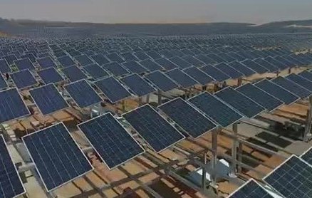 Rows of blue solar panels on metal frames across dry ground.