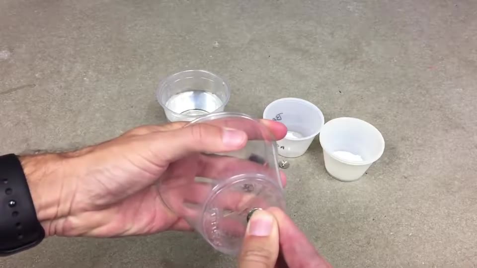Plastic cups of liquid set up for a battery electrolysis demo