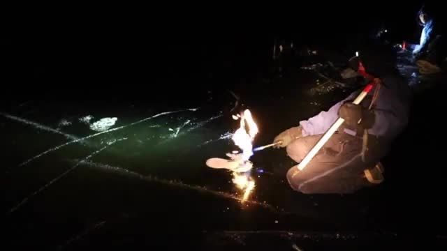 A flame burning on the ice where methane is being lit.