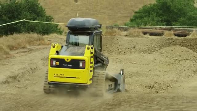 A small track loader pushing a pile of dirt.