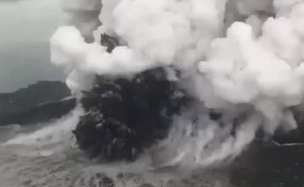 A dark eruption column rising from Anak Krakatau into the sea.