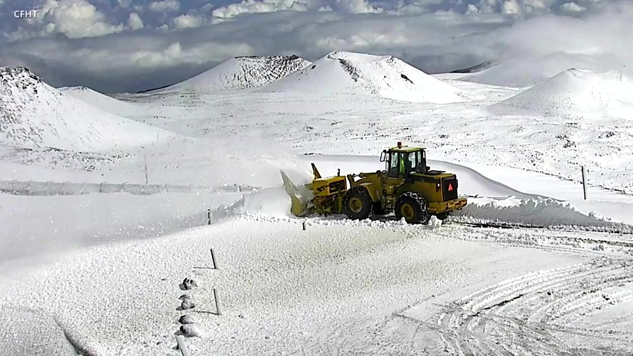 Yellow snowblower clearing a road on snowy Mauna Kea summit