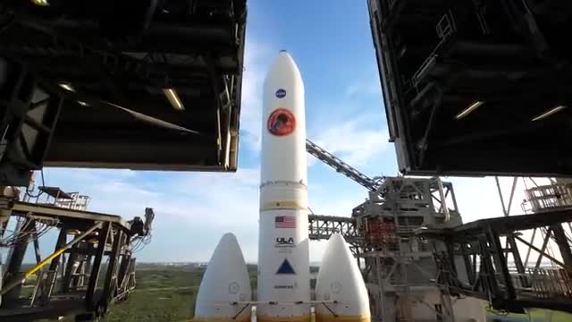 A white rocket standing between the open doors of a launch tower.