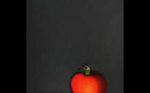 A red tomato glowing under a narrow beam of light.