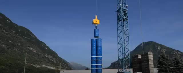 A crane stacking blue weights into a tall column.