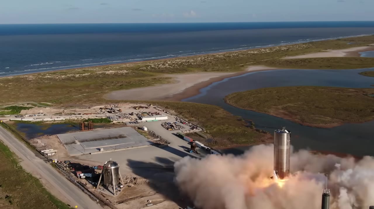 Starship prototype lifting off a coastal pad in a cloud of dust