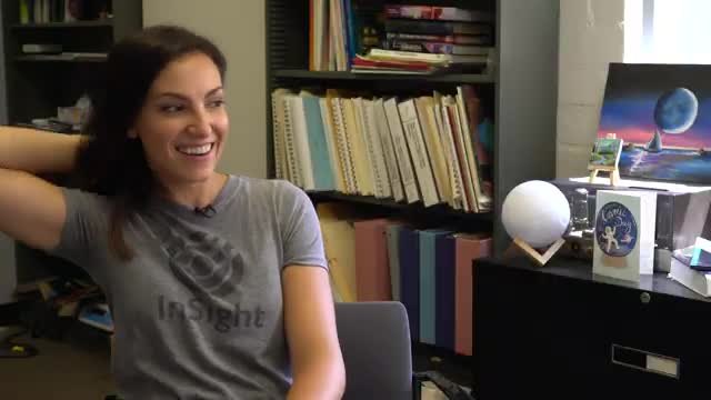 A scientist in an office with a globe and a painting of a planet on the cabinet.