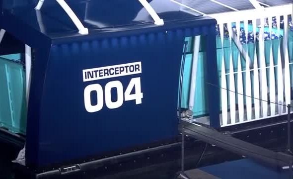 Blue river-trash collector marked Interceptor 004, beside a white railing.