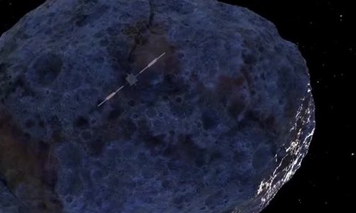A cratered metal-rich asteroid with a small spacecraft and its long antenna in front.
