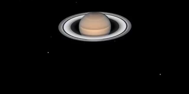 Saturn and its rings, with small moons as points of light.