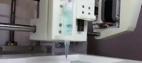 A printer nozzle above a small dish.