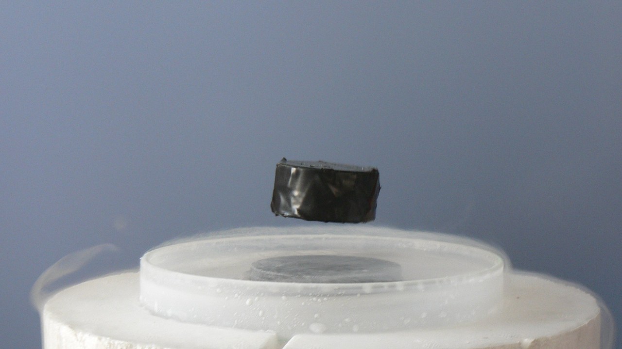 A magnet levitating above a superconductor cooled by liquid nitrogen