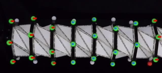 Folded white lattice with colored tracking markers along a repeating origami structure