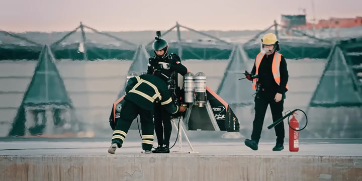 Two people in flight suits with jet wings standing on a pad
