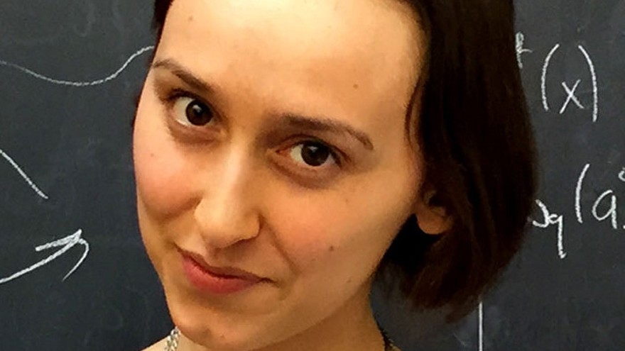 Physicist Sabrina Gonzalez Pasterski in front of a chalkboard covered in equations.