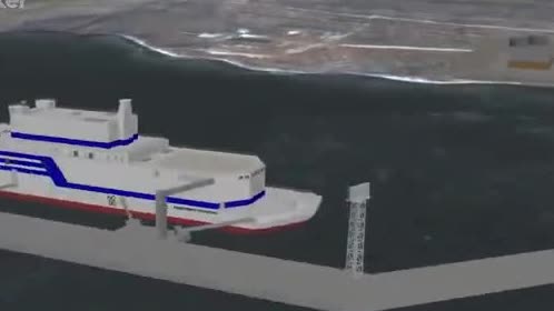 A barge carrying a nuclear power plant alongside a dock