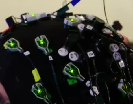 A black cap covered with glowing electrode sensors and wires.