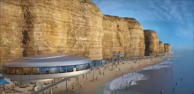 A round station on stilts along a beach cliff.
