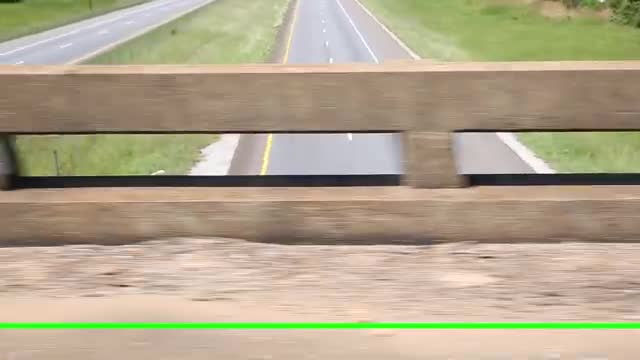 A highway seen past a concrete barrier, with a bright scan line
