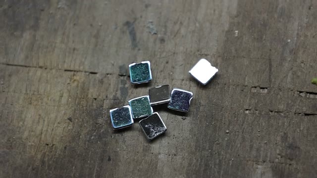 Four small dark solar-cell samples on a wooden bench
