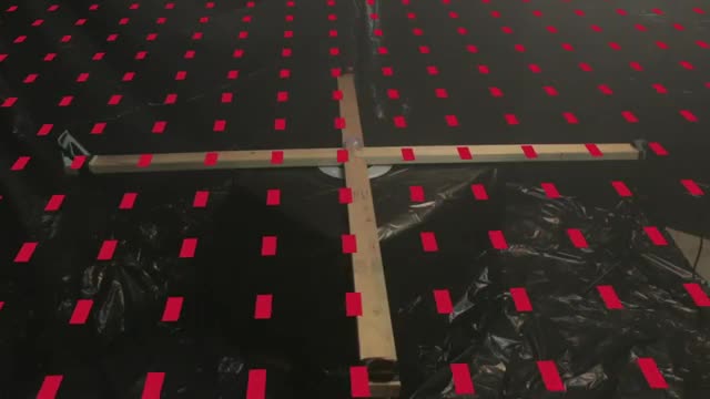 A wooden cross on a grid of red marks